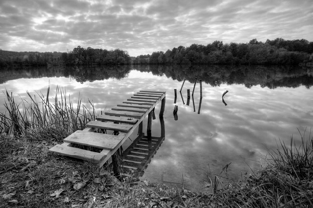 Beautiful lake with pier on cloudy day in black and white